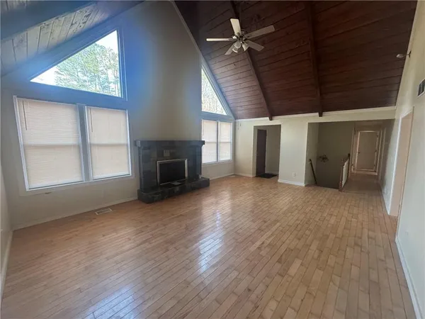 an empty room with wooden floor fireplace and windows