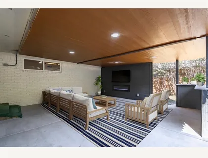 a living room with furniture a flat screen tv and a floor to ceiling window