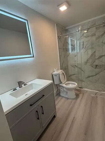 a bathroom with a granite countertop sink a toilet and a mirror