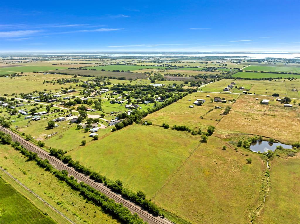 1795 Melton Road Sanger, TX 76266 - Photo 12 of 17 Expansive rural landscape featuring a body of water in the distance, agricultural fields, a small community of structures, a railway track, and a small pond