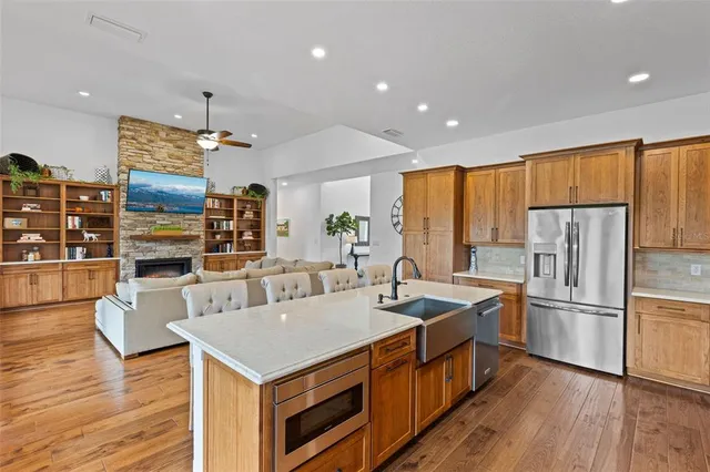 a kitchen with stainless steel appliances granite countertop a refrigerator a stove and a wooden floors