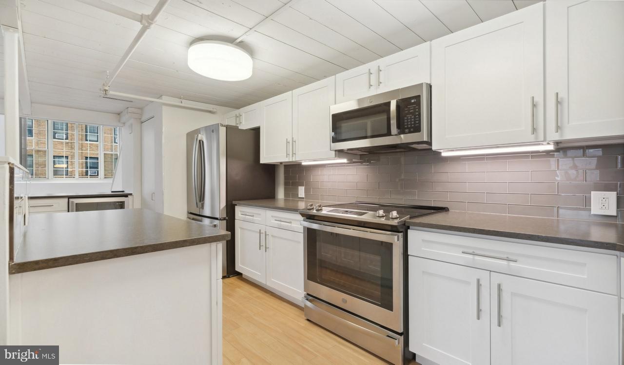 a kitchen with stainless steel appliances granite countertop white cabinets a microwave a sink and a refrigerator