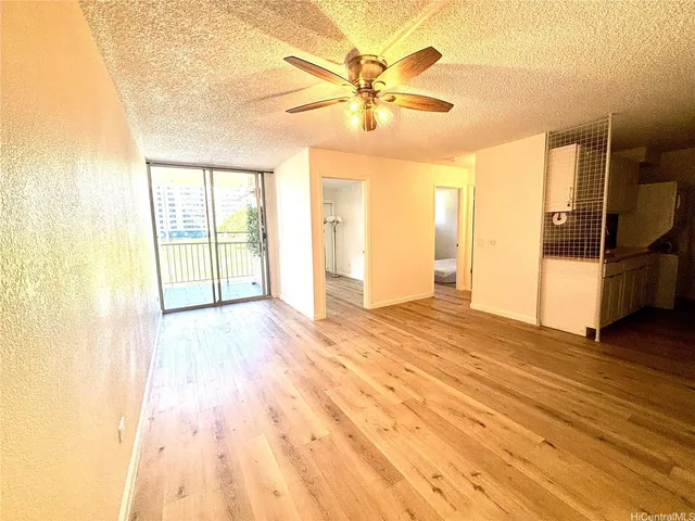 a view of empty room with wooden floor and fan