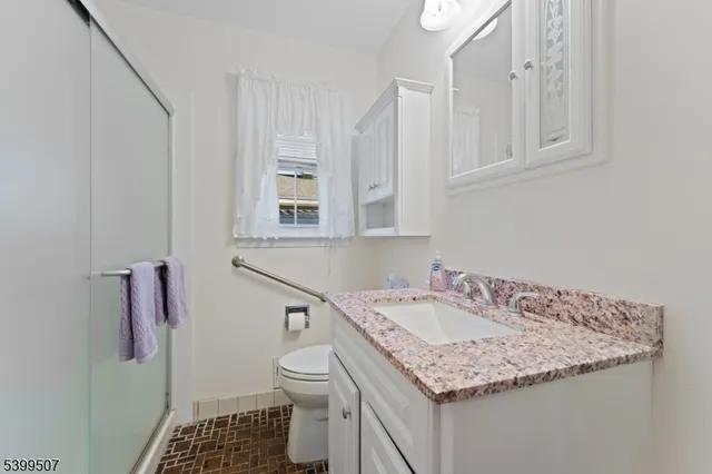 a bathroom with a granite countertop sink and a toilet