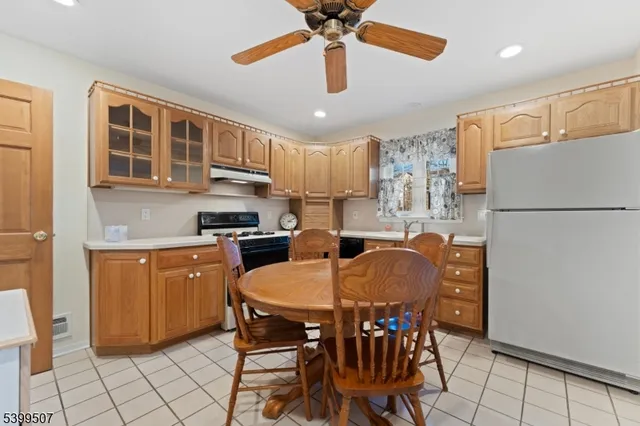 a kitchen with stainless steel appliances granite countertop a refrigerator a sink a stove a dining table and chairs with wooden floor