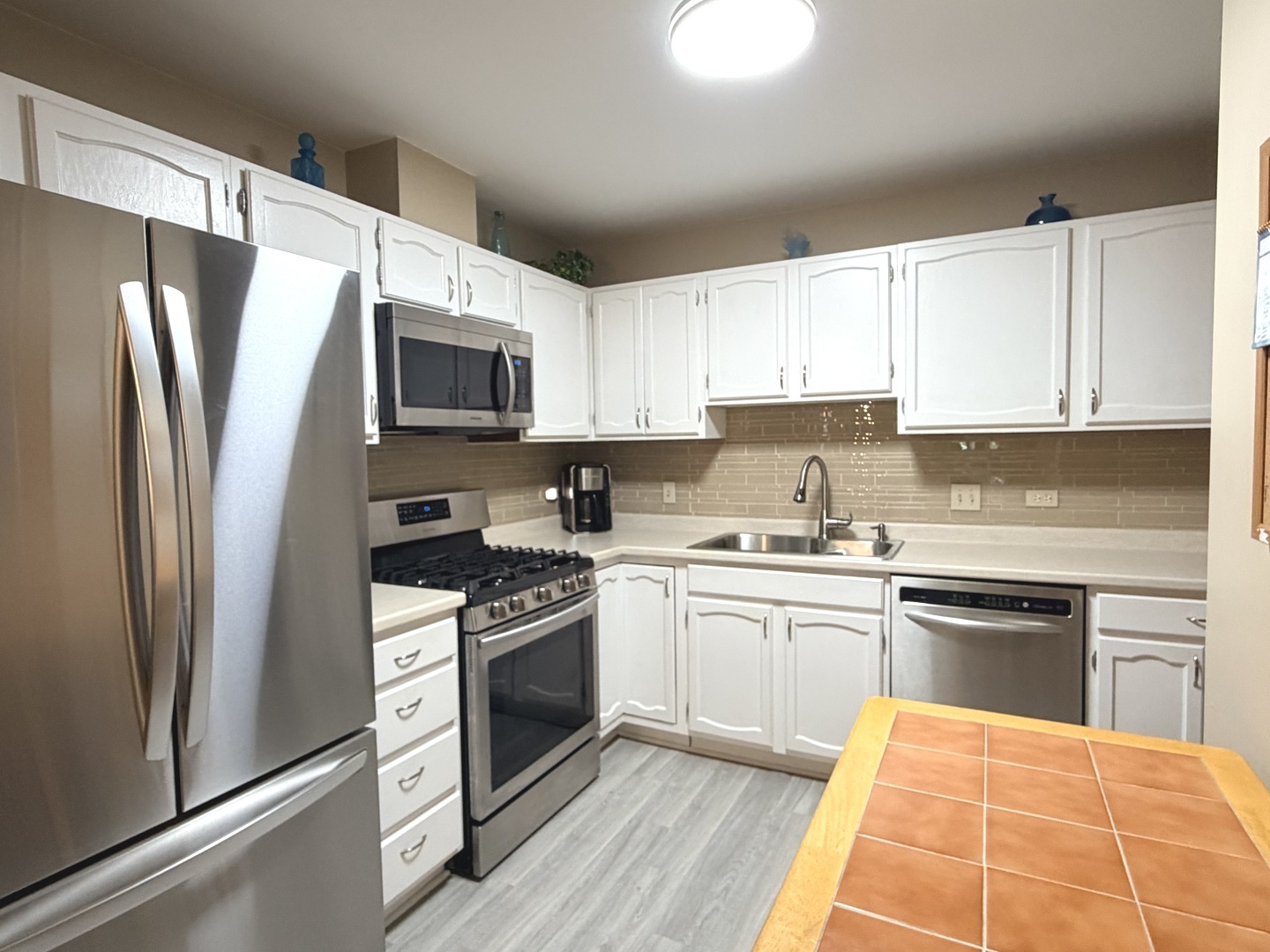 300 East Dundee Road, Unit 102A Buffalo Grove, IL 60089 - Photo 3 of 27 a kitchen with stainless steel appliances granite countertop a stove top oven a refrigerator and a sink with wooden floor