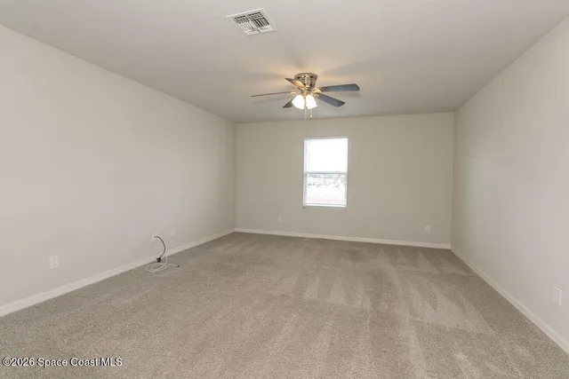 an empty room with a window and ceiling fan