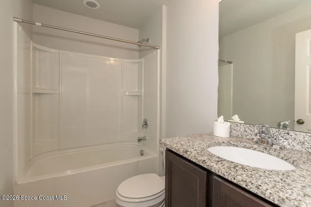 a bathroom with a granite countertop sink a toilet and shower