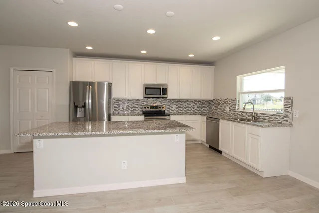 a large kitchen with stainless steel appliances granite countertop a stove a sink a refrigerator and a granite counter tops