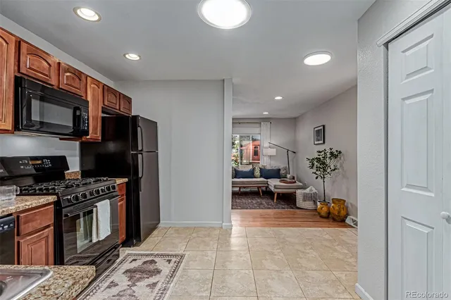a view of kitchen with stainless steel appliances kitchen island granite countertop a stove a refrigerator a sink a dining table and chairs with wooden floor