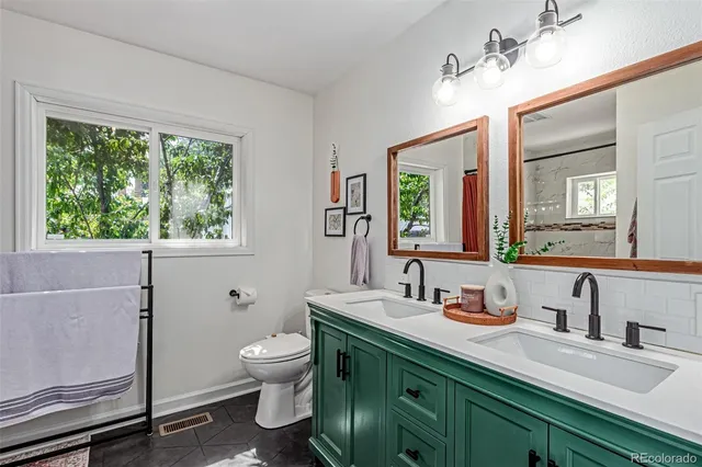 a bathroom with a granite countertop sink a toilet a mirror and a window
