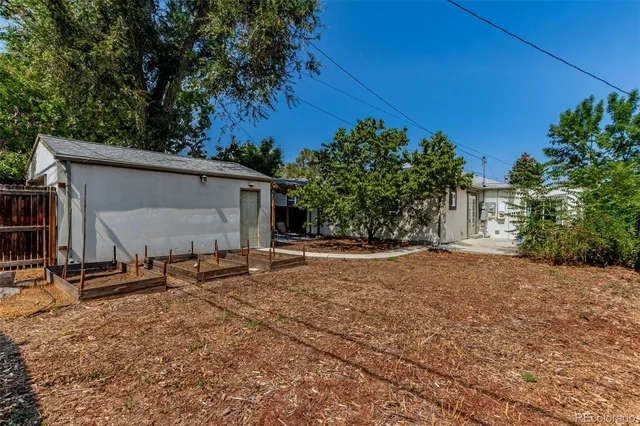 a backyard of a house with table and chairs under an umbrella