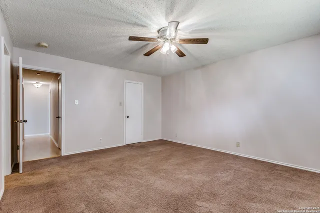 an empty room with ceiling fan and window
