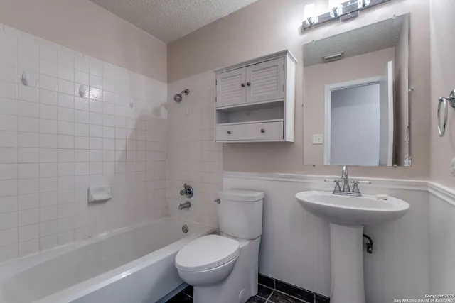 a bathroom with a toilet a sink a mirror a bathtub and vanity