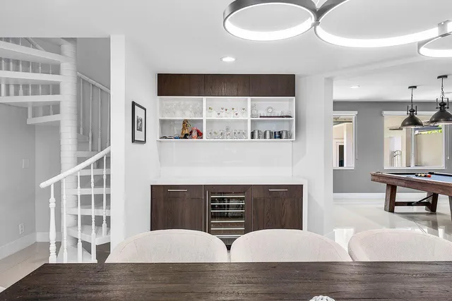 a living room with stainless steel appliances furniture a fireplace and cabinets