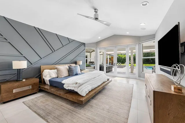 a bedroom with a large bed a flat screen tv and a large window