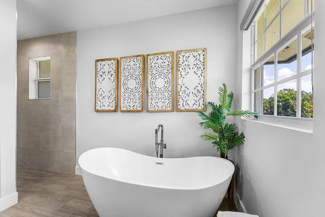 a white bath tub sitting in a bathroom next to a window