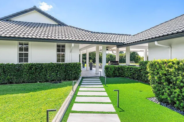 a front view of a house with a yard and potted plants