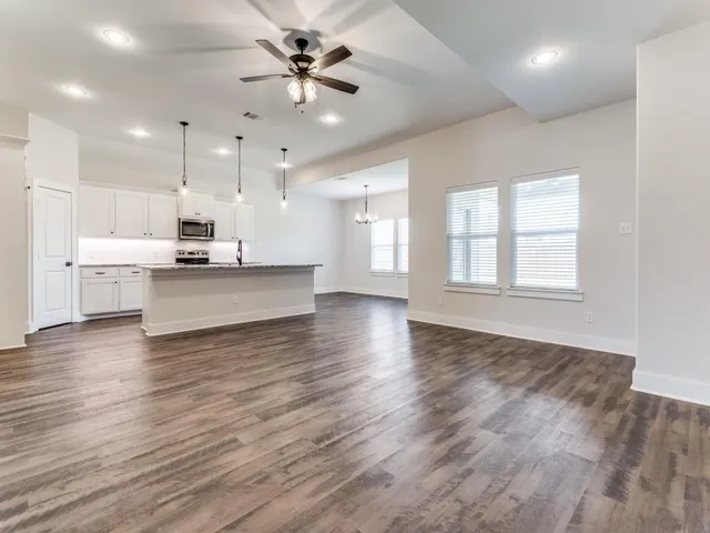a view of a kitchen with kitchen island a sink wooden floor and a window