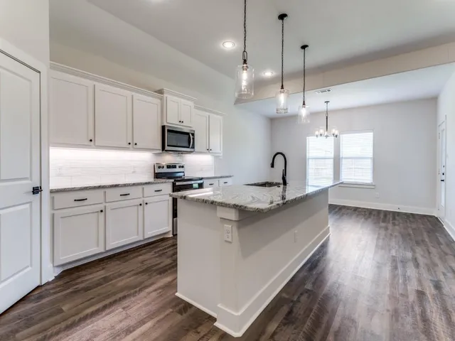 a kitchen with granite countertop a sink cabinets and wooden floor