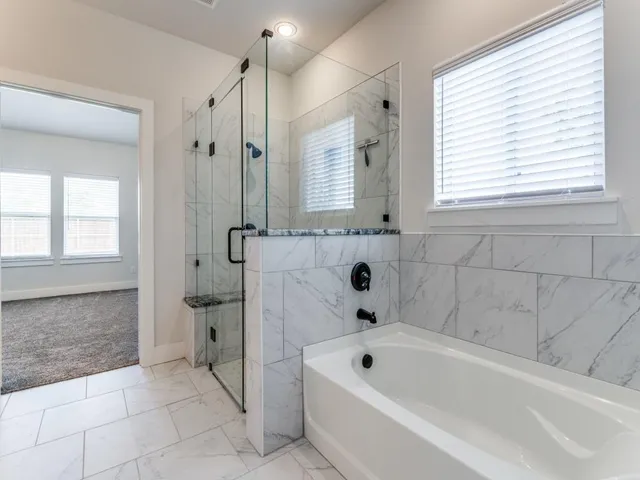 a bathroom with a bathtub a window and a shower
