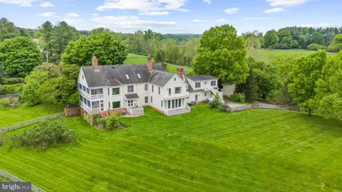 an aerial view of residential house with outdoor space and trees all around