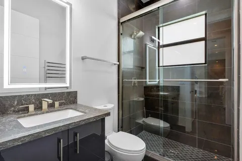 a bathroom with a granite countertop sink toilet a mirror and shower