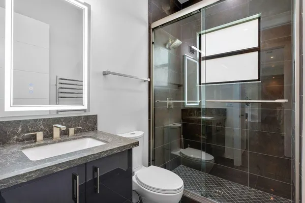 a bathroom with a granite countertop sink toilet a mirror and shower