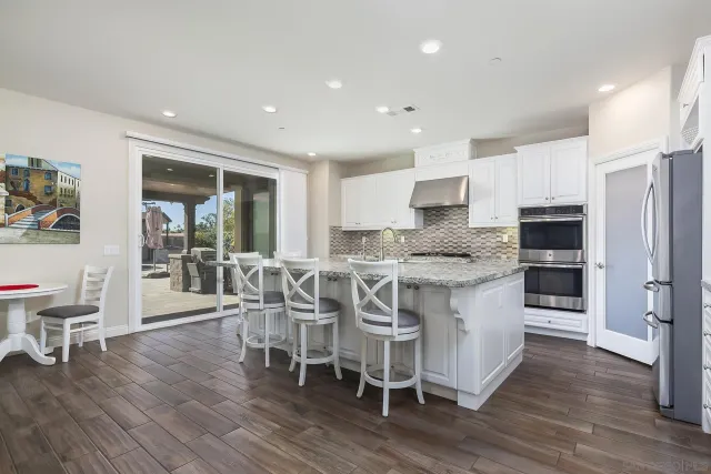 a large kitchen with kitchen island granite countertop lots of white cabinets a sink and stainless steel appliances