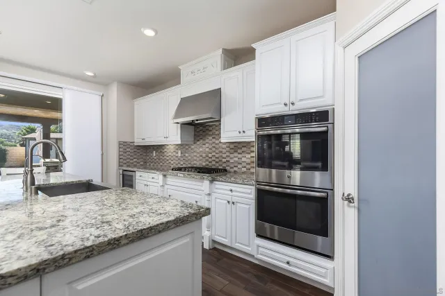 a living room with furniture kitchen view and a wooden floor