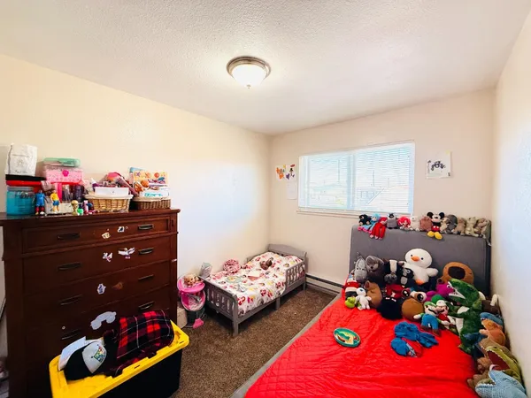a bedroom with a bed dresser and a children play room