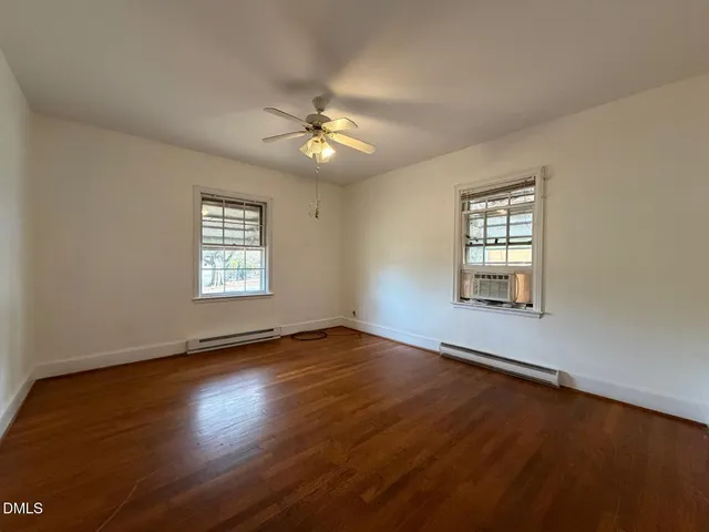 a view of an empty room with a window and wooden floor