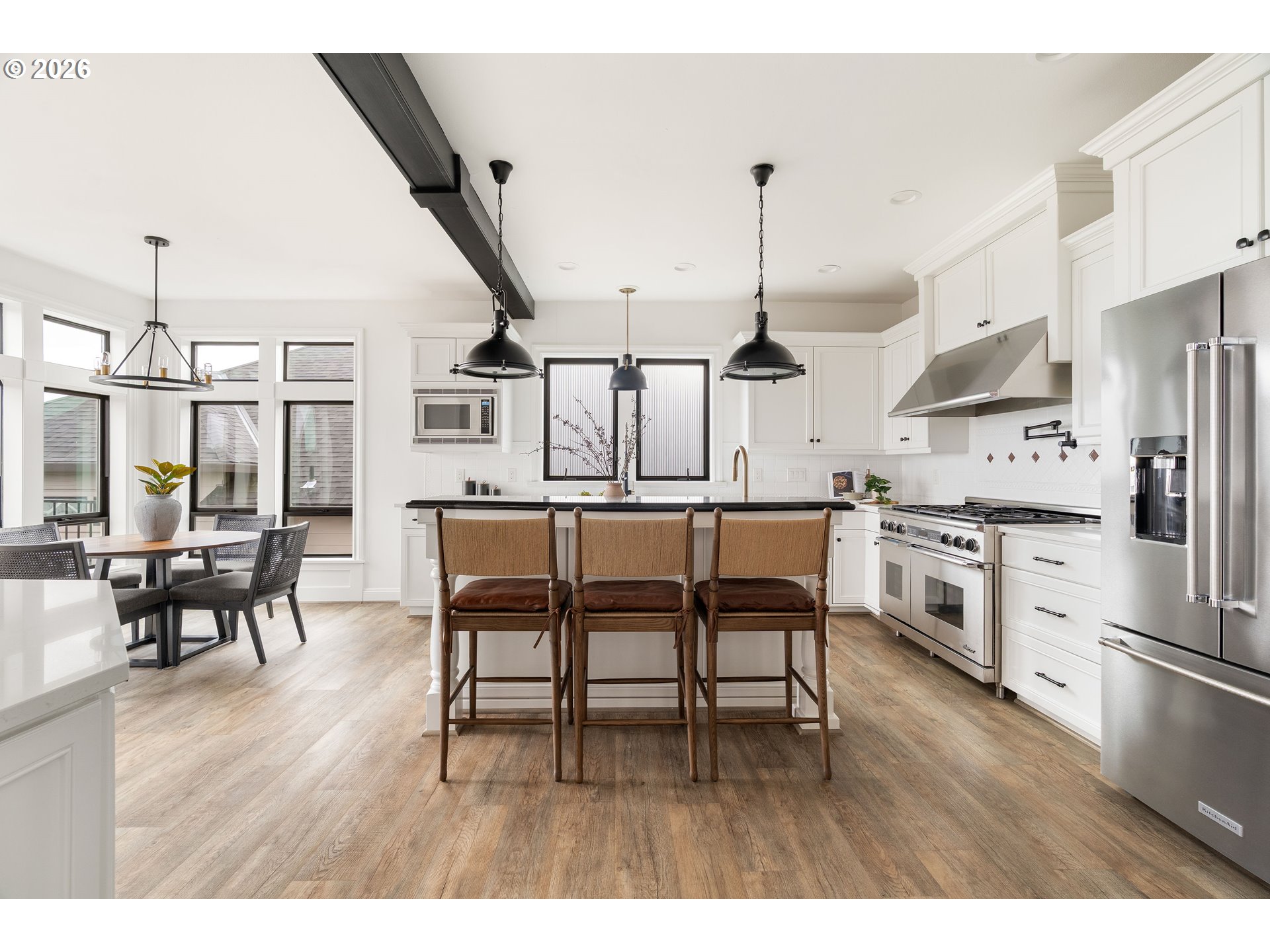 10230 Northwest Gloaming Lane Portland, OR 97229 - Photo 10 of 48 a kitchen with stainless steel appliances kitchen island granite countertop a table chairs stove and white cabinets