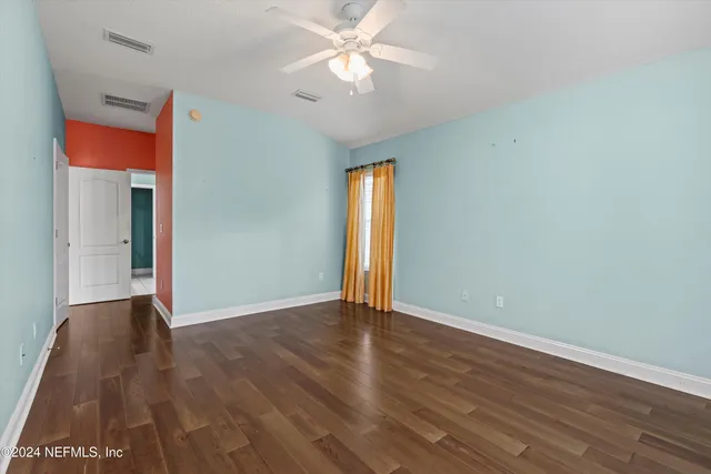 an empty room with wooden floor closet and windows