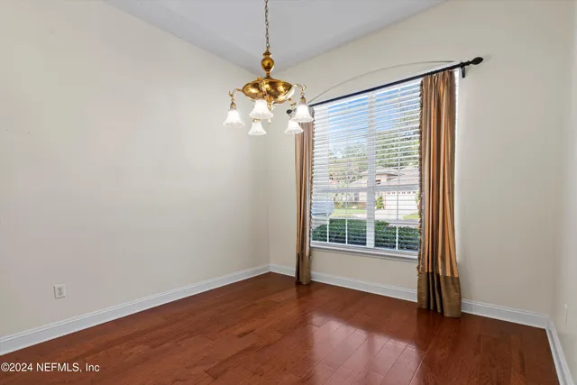 a view of a livingroom with wooden floor a chandelier and a window