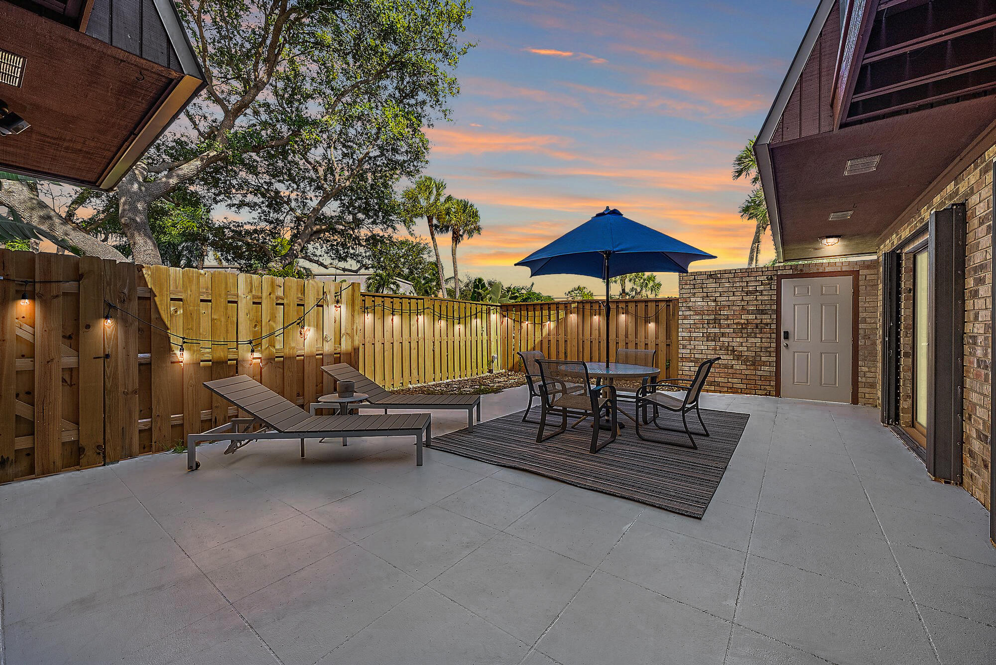 1420 Ocean Way, Unit 30C Jupiter, FL 33477 - Photo 4 of 25 a view of a patio with a table and chairs under an umbrella with a small yard