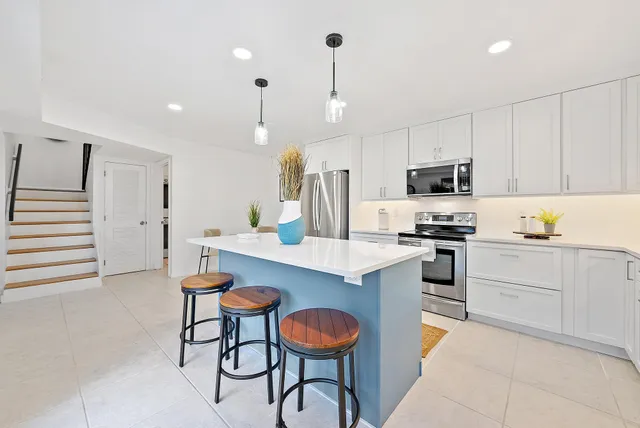 a kitchen with stainless steel appliances granite countertop a sink a stove a refrigerator and chairs