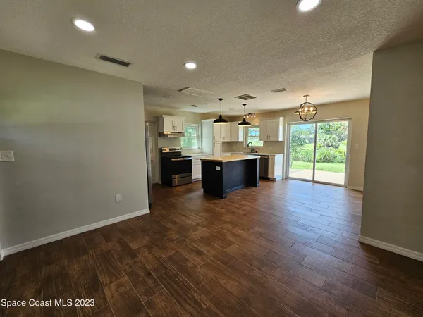 a view of kitchen with kitchen island wooden floors and stainless steel appliances