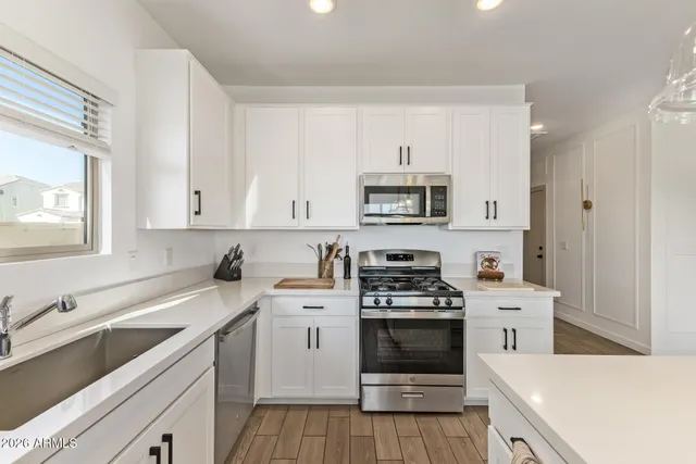 a kitchen with stainless steel appliances kitchen island granite countertop a table chairs sink and cabinets