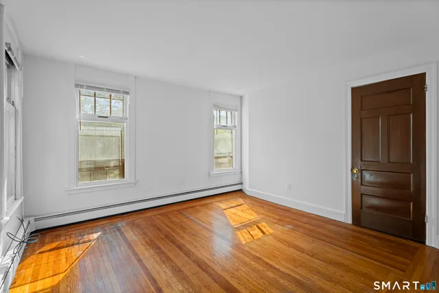 an empty room with wooden floor closet and windows