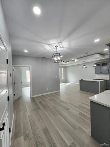 a view of a hallway with wooden floor and a kitchen