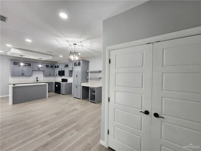 a large white kitchen with kitchen island a sink white cabinets and stainless steel appliances