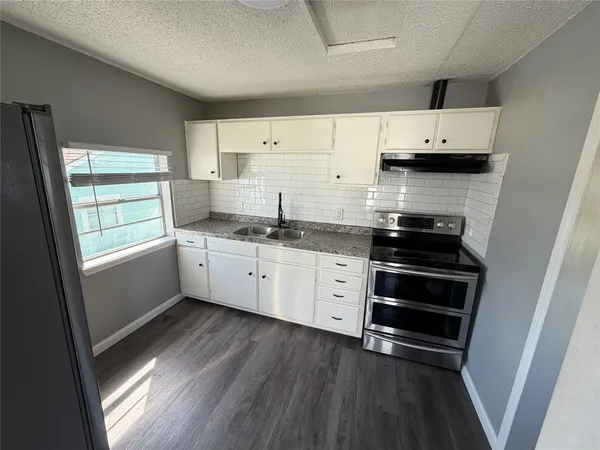a kitchen with stainless steel appliances a sink cabinets and a wooden floor
