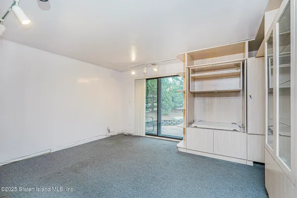 a view of an empty room with a cabinet and mirrors