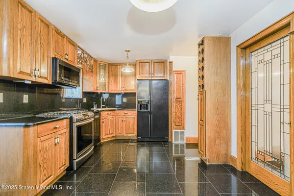 a kitchen with stainless steel appliances granite countertop a refrigerator a stove and a sink with wooden floors