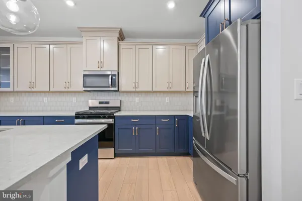 a kitchen with stainless steel appliances granite countertop a refrigerator a stove a sink and white cabinets