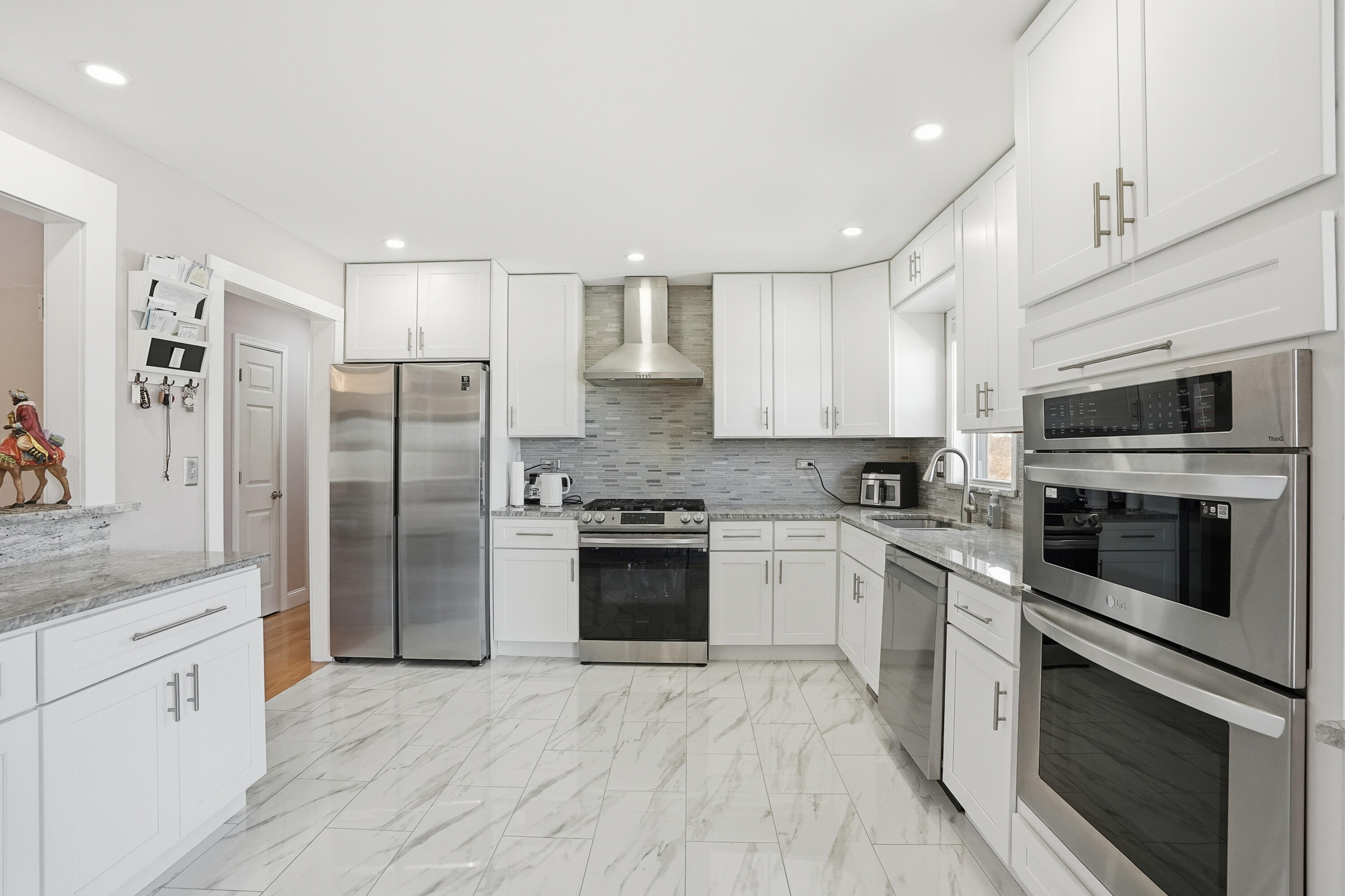 11109 Iowa Street Crown Point, IN 46307 - Photo 6 of 31 a kitchen with stainless steel appliances granite countertop a refrigerator oven a sink dishwasher and white cabinets with wooden floor