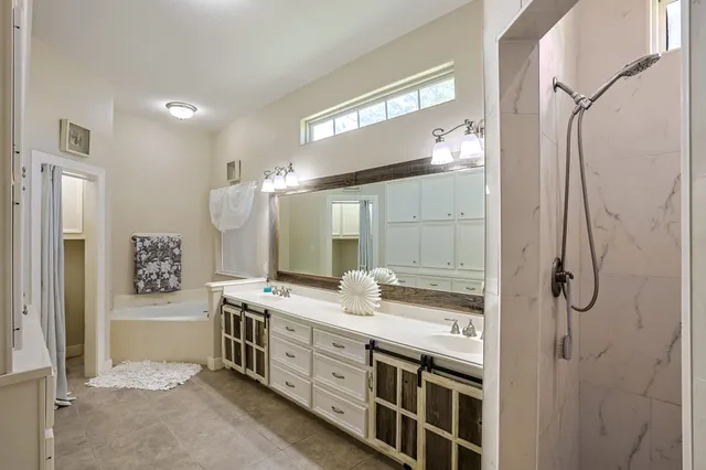 a spacious bathroom with a double vanity sink a mirror and a shower