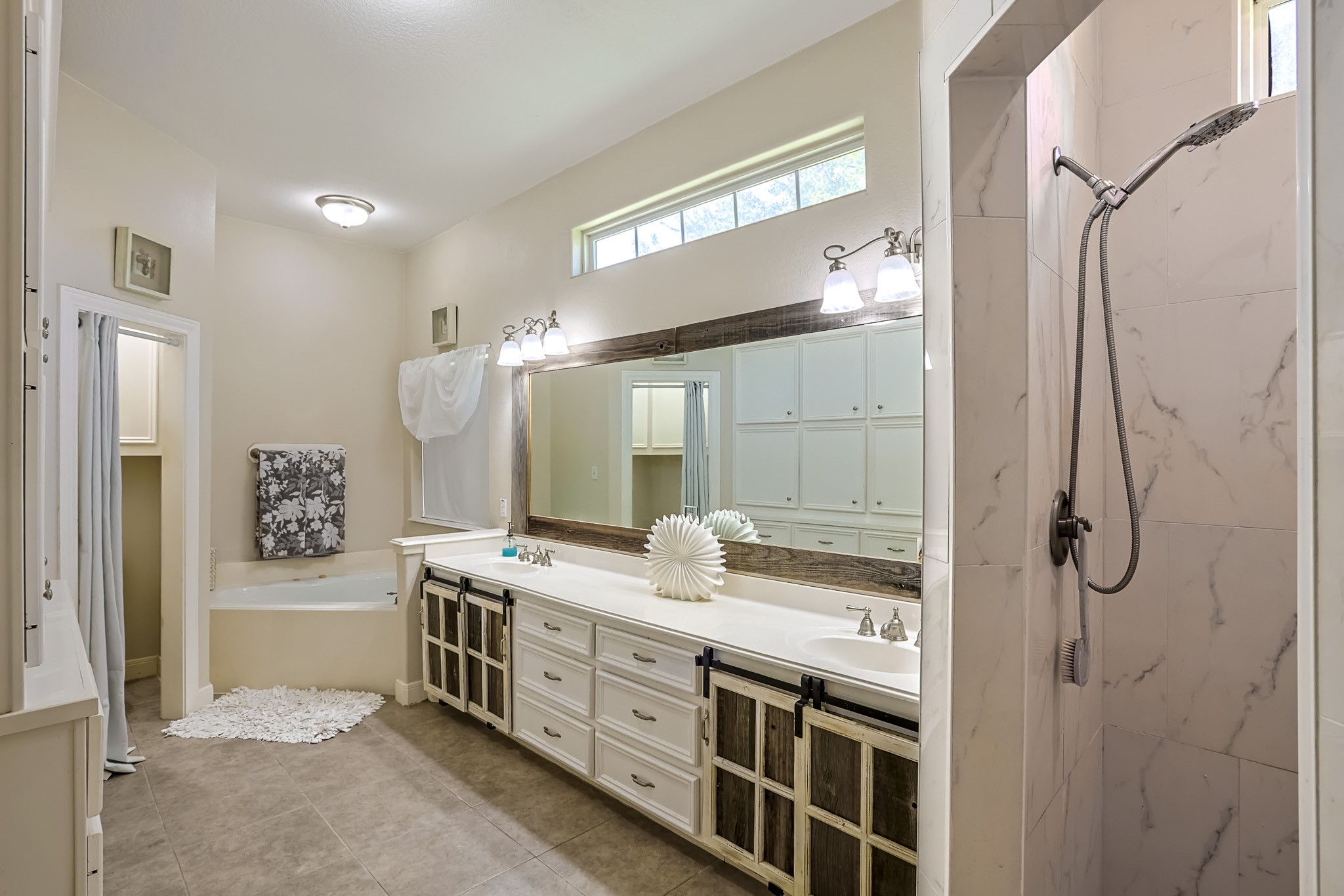 30119 West Geneva Drive Spring, TX 77386 - Photo 25 of 49 Luxurious en-suite bath with dual vanities, a large framed mirror, and abundant cabinet storage accented by charming barn-style details