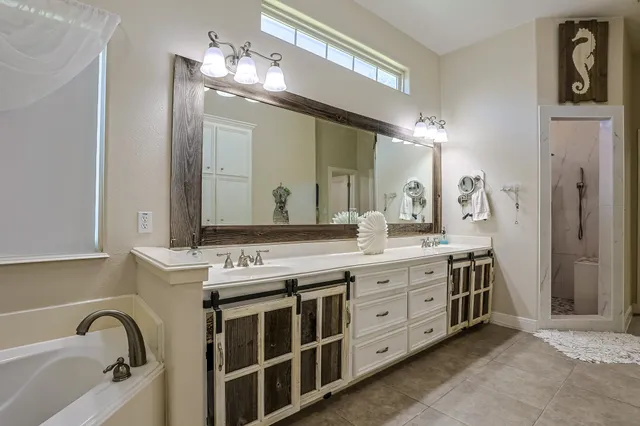 a bathroom with a double vanity sink mirror and bathtub